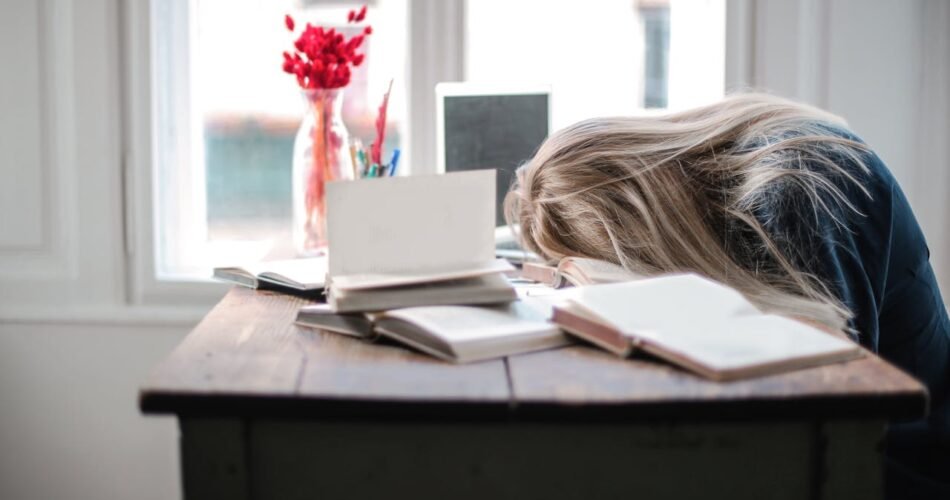 Femme épuisée endormie sur son bureau de travail avec ordinateur portable, illustrant l'importance d'utiliser un calculateur de sommeil pour optimiser ses cycles de repos et éviter la fatigue chronique
